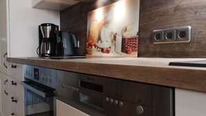 Een keuken met een koffiezetapparaat, een magnetron en een broodrooster. Er is een houten aanrecht en een wandcontactdoos.