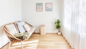 A cozy living room with a wicker sofa, a small side table, and a potted plant. - JB’s - Jetty Busselton Stay (West Busselton)