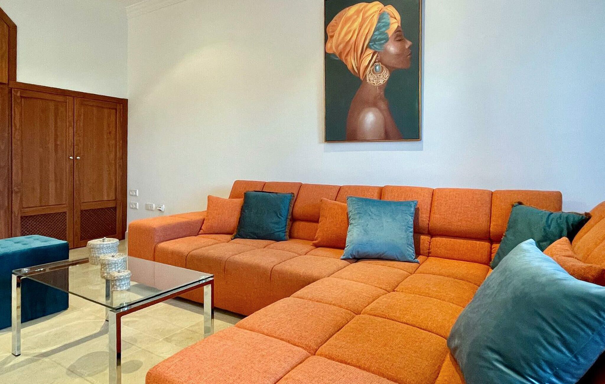 A living room with a sectional sofa, a glass coffee table, and a wooden wardrobe.