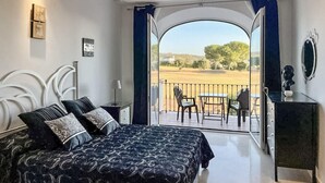 A bedroom with a bed, a nightstand, a dresser, and a balcony with chairs and a table. - 2 bedroom nice home in Arcos de la Frontera (Arcos de la Frontera)