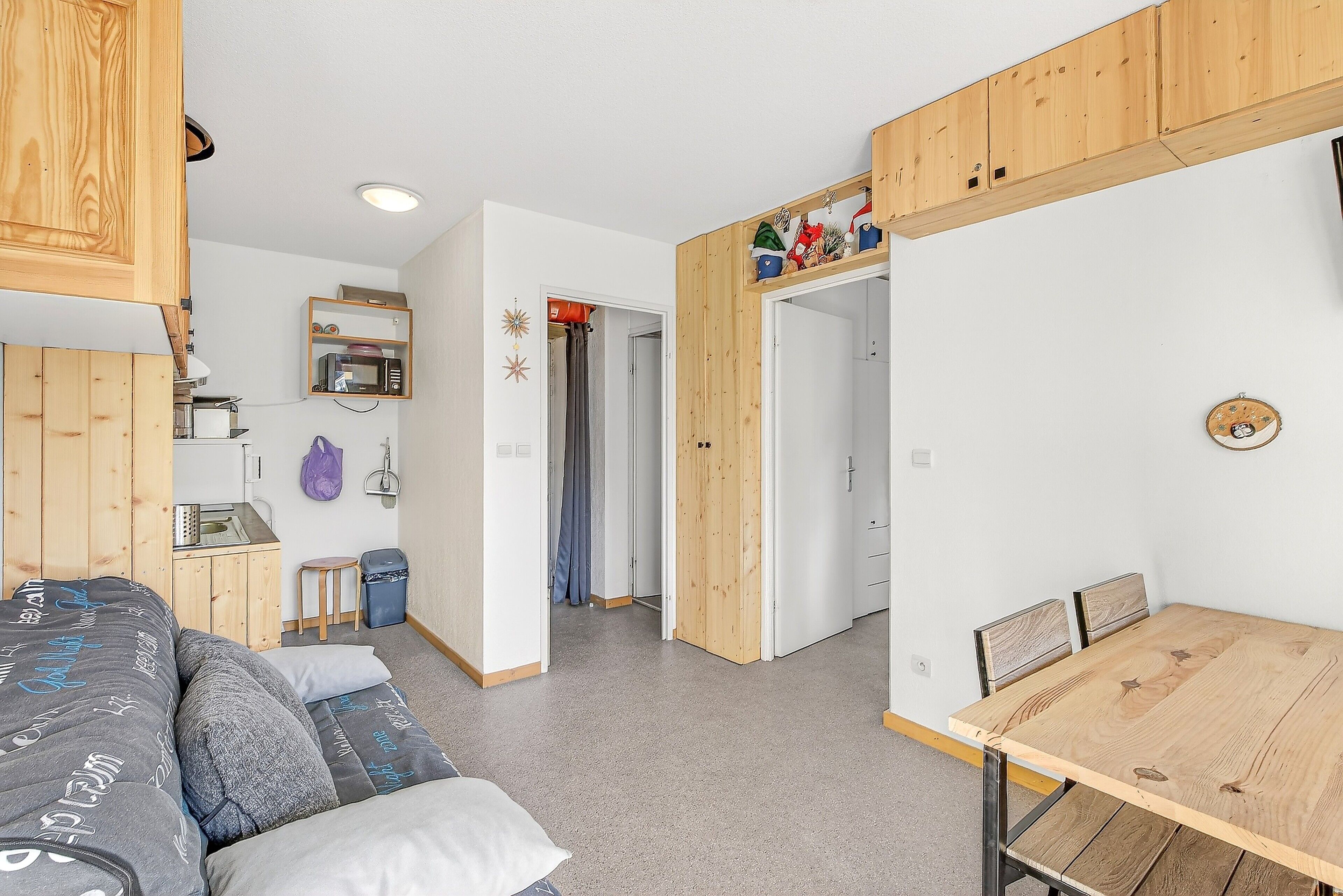 Une petite pièce comprenant un lit, une petite table et un meuble en bois.