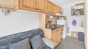 A compact kitchen with wooden cabinets, a built-in microwave, and a small countertop. - 'Superdevoluy' Apartment with Mountain View and Balcony (Dévoluy)