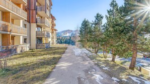 A pathway flanked by multi-story buildings with balconies, leading to a mountainous backdrop. - 'Superdevoluy' Apartment with Mountain View and Balcony (Dévoluy)