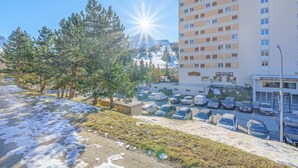 A parking lot with cars, a building with multiple floors, and a mountain in the background. - 'Superdevoluy' Apartment with Mountain View and Balcony (Dévoluy)
