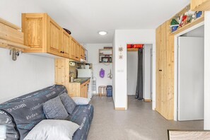 A compact living space with a kitchenette, a sofa, and a door leading to another room. - 'Superdevoluy' Apartment with Mountain View and Balcony (Dévoluy)