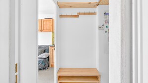 A narrow hallway with a wooden bench, a coat rack, and a door leading to a room with a bed and a wooden cabinet. - 'Superdevoluy' Apartment with Mountain View and Balcony (Dévoluy)