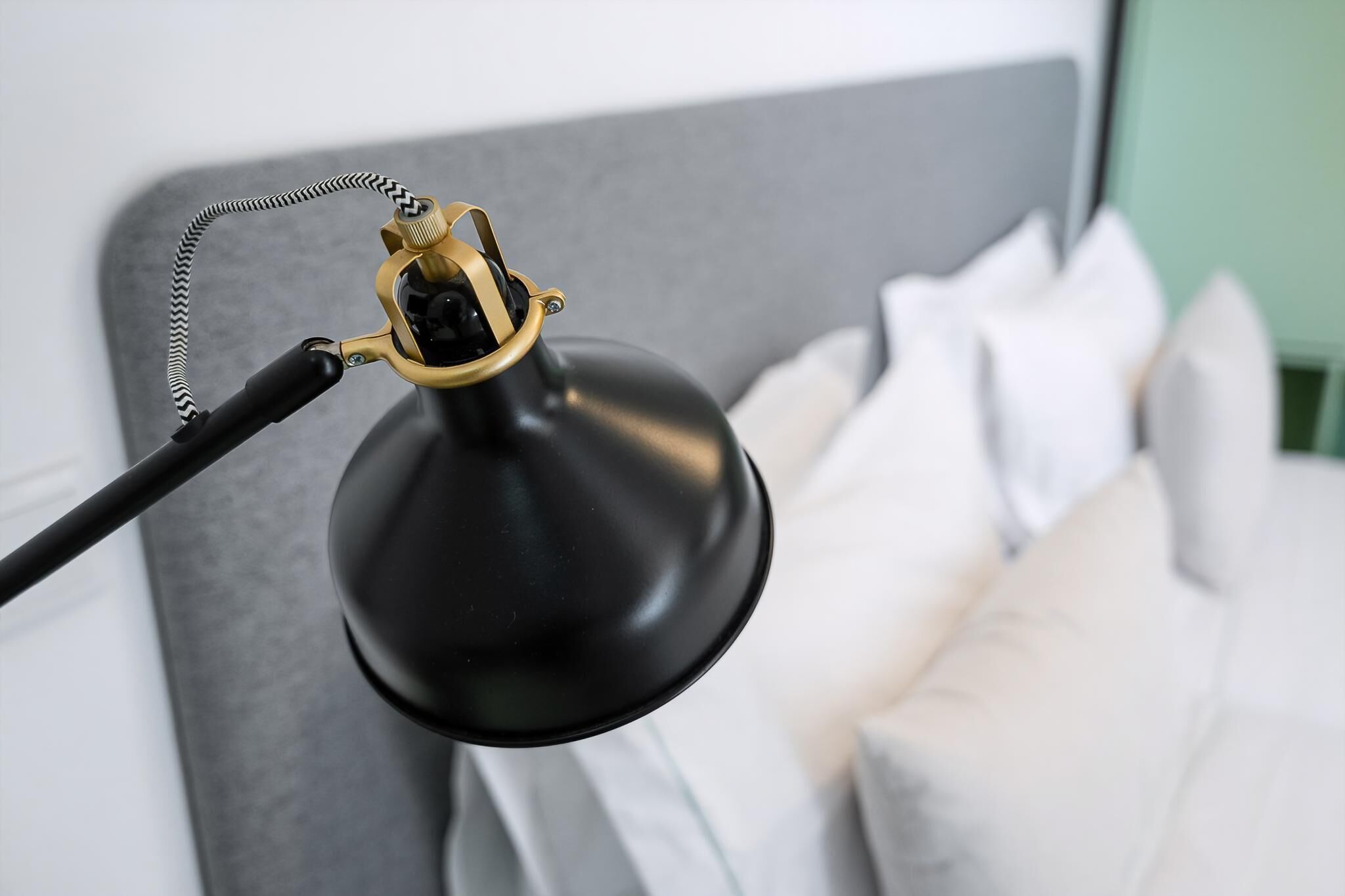 A black desk lamp with a gold-colored base and a braided cord.