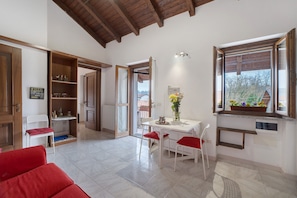 A spacious room with a dining area, a red sofa, and a view through a window.