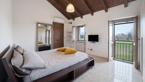 Ein Schlafzimmer mit einem Bett, einem Fernseher, einem großen Spiegel und einem Balkon.
