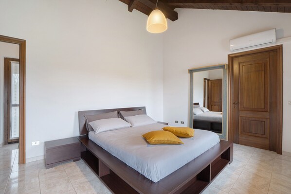 Une chambre à coucher avec un lit, une table de chevet, un miroir et une armoire.