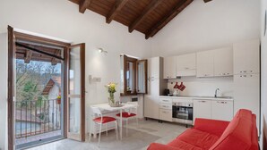 Eine moderne Küche mit weißen Schränken, ein Essbereich mit Tisch und Stühlen sowie ein rotes Sofa.