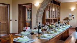 A long dining table set for a meal with wine glasses, plates, and a bottle of wine. - Podere Gellino 14, Emma Villas (Chianciano Terme)