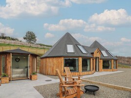A wooden cabin with a sauna, a hot tub, and a grill area.
