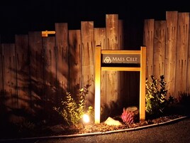 A wooden fence with a sign that reads "Maes Celt Talcrown Roundhouses."