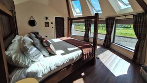 Une chambre avec un grand lit, des fenêtres de toit et une vue sur l’extérieur.