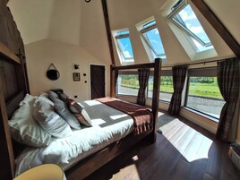 A bedroom with a large bed, skylights, and a view of the outdoors.