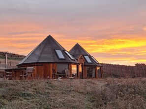 Two wooden cabins with pitched roofs and skylights, surrounded by a grassy field. - Yr Awen - Inspiration (Lampeter)