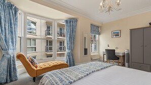 A bedroom with a large bed, a chaise lounge, a desk, and a wardrobe. - Lan Y Mor - Close to Town and Beach (Tenby)