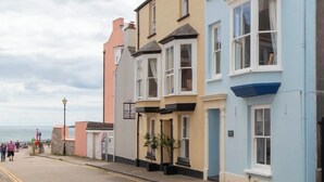 A row of colorful terraced houses along a cobblestone street with a view of the sea in the background. - Lan Y Mor - Close to Town and Beach (Tenby)