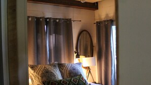 Ein Schlafzimmer mit Bett, Vorhängen, einer Lampe und einem Spiegel.