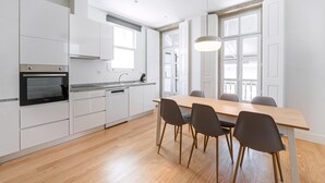A modern kitchen with white cabinets, a wooden dining table, and four chairs. - Guestready - RNB Apartments (Porto)