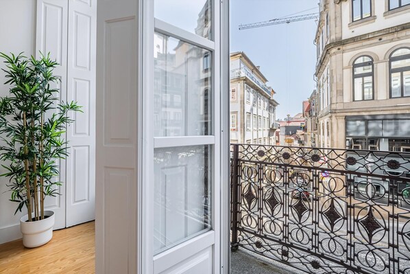 A balcony with a wrought iron railing, a potted plant, and a view of historic buildings. - Guestready - RNB Apartments (Porto)