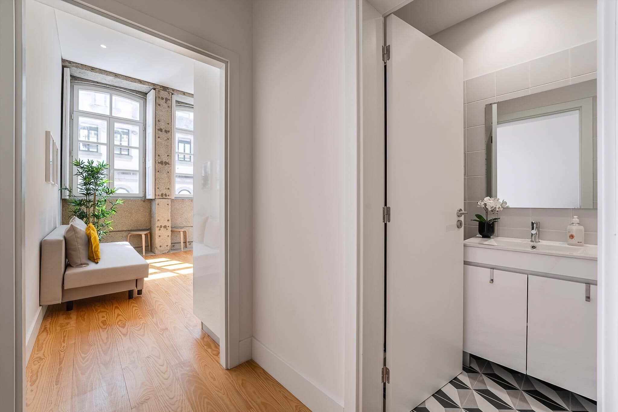 A modern bathroom with a large mirror, white cabinets, and a tiled floor.