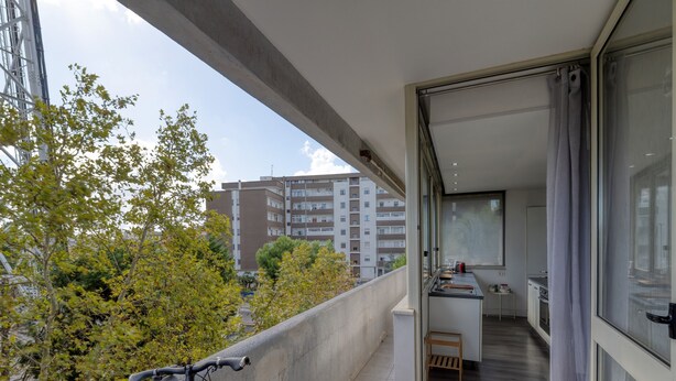 A balcony with a bicycle, a view of a residential area, and a glimpse of an interior with a kitchen and dining area. - Spacious Central Apartment with Wi-Fi and Portable Air Conditioning (Lecce)