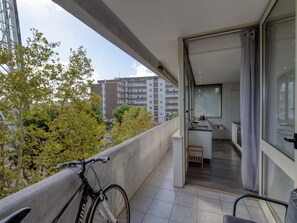 A balcony with a bicycle, a view of a residential area, and a glimpse of an interior with a kitchen and dining area. - Spacious Central Apartment with Wi-Fi and Portable Air Conditioning (Lecce)