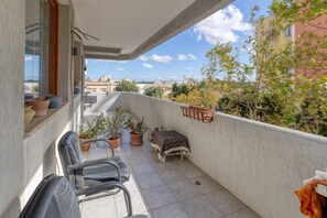 Un balcon agrémenté de plantes en pot, une petite table et des chaises.