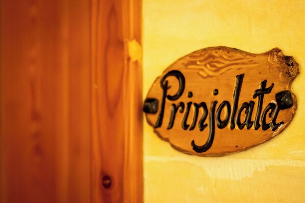 A wooden sign with the word "Prijolate" on a yellow wall.
