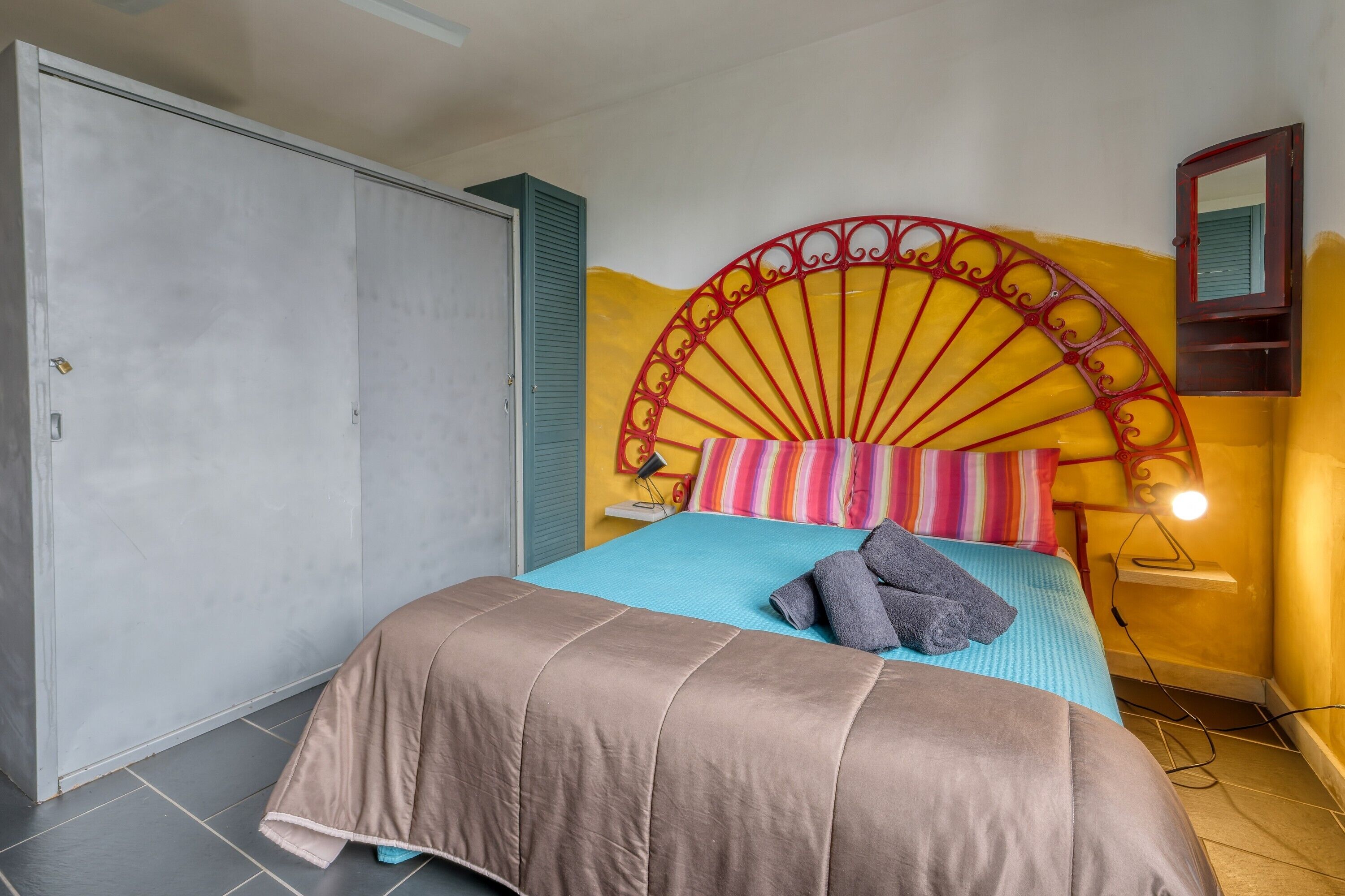 A bed with a headboard, a wardrobe, and a wall-mounted shelf with a lamp.