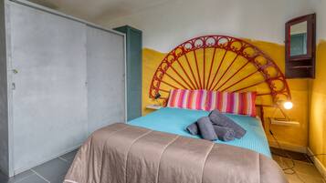 A bed with a headboard, a wardrobe, and a wall-mounted shelf with a lamp.