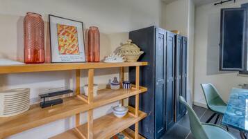 A modern kitchen with wooden shelves, a dining table, green chairs, and a black refrigerator.