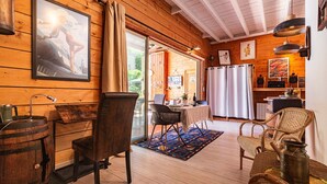 A wooden interior with a dining area, chairs, a table, and a bar area with a counter and stools. - Gîte La Grange de Soyons (Soyons)
