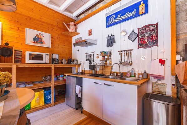 Una cocina con paredes de madera, un letrero colgante de Ballantine's, un microondas y varios utensilios de cocina.