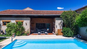 A modern house with a swimming pool, a patio with outdoor furniture, and a large window overlooking the pool. - Gîte La Grange de Soyons (Soyons)
