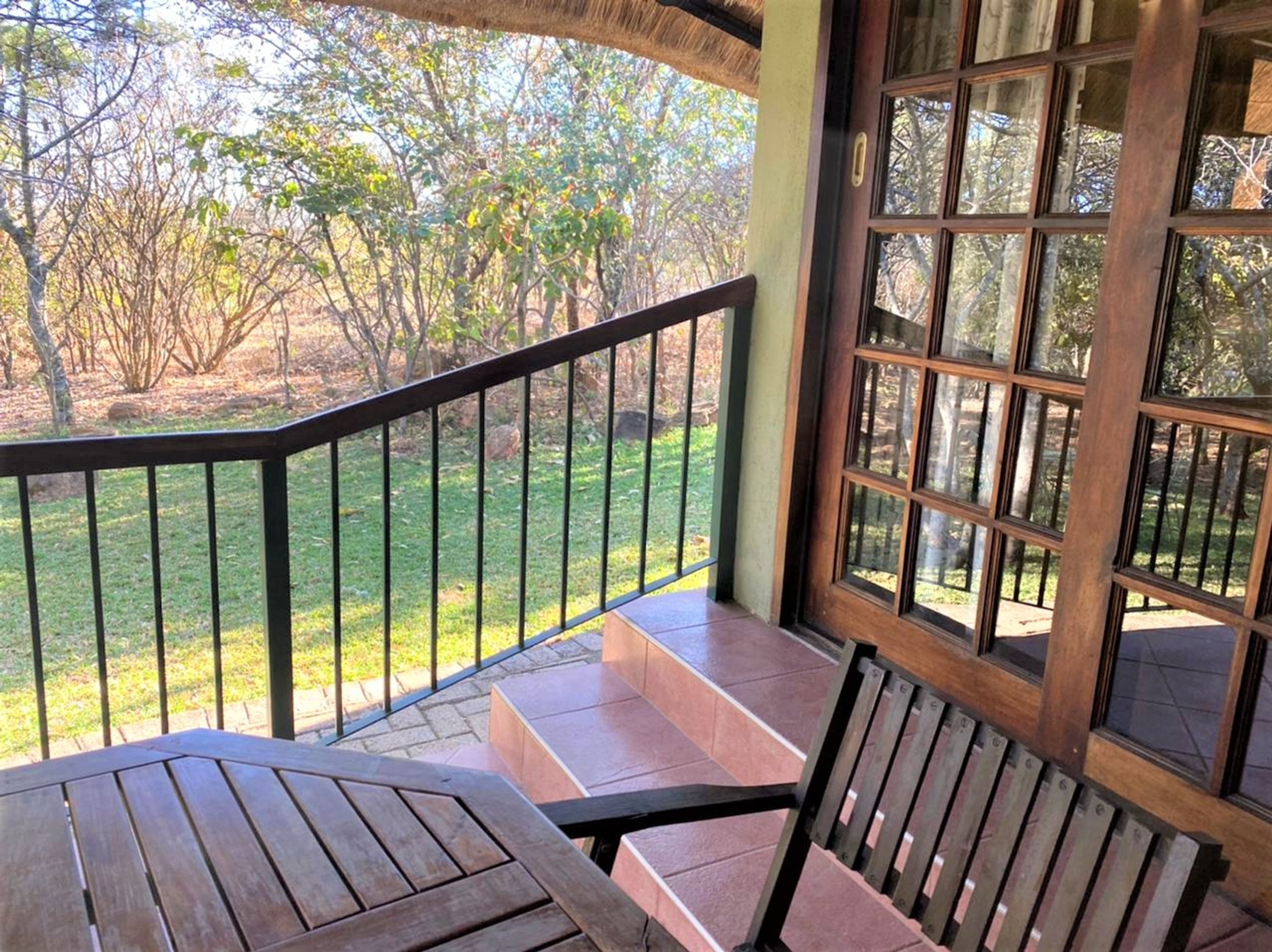 A covered outdoor seating area with a view of a grassy landscape and trees.