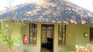 A thatched-roof building with a stone wall, a fire extinguisher, and a statue. - Double Lodge in Natural African Bush - 2112 (Bulawayo)
