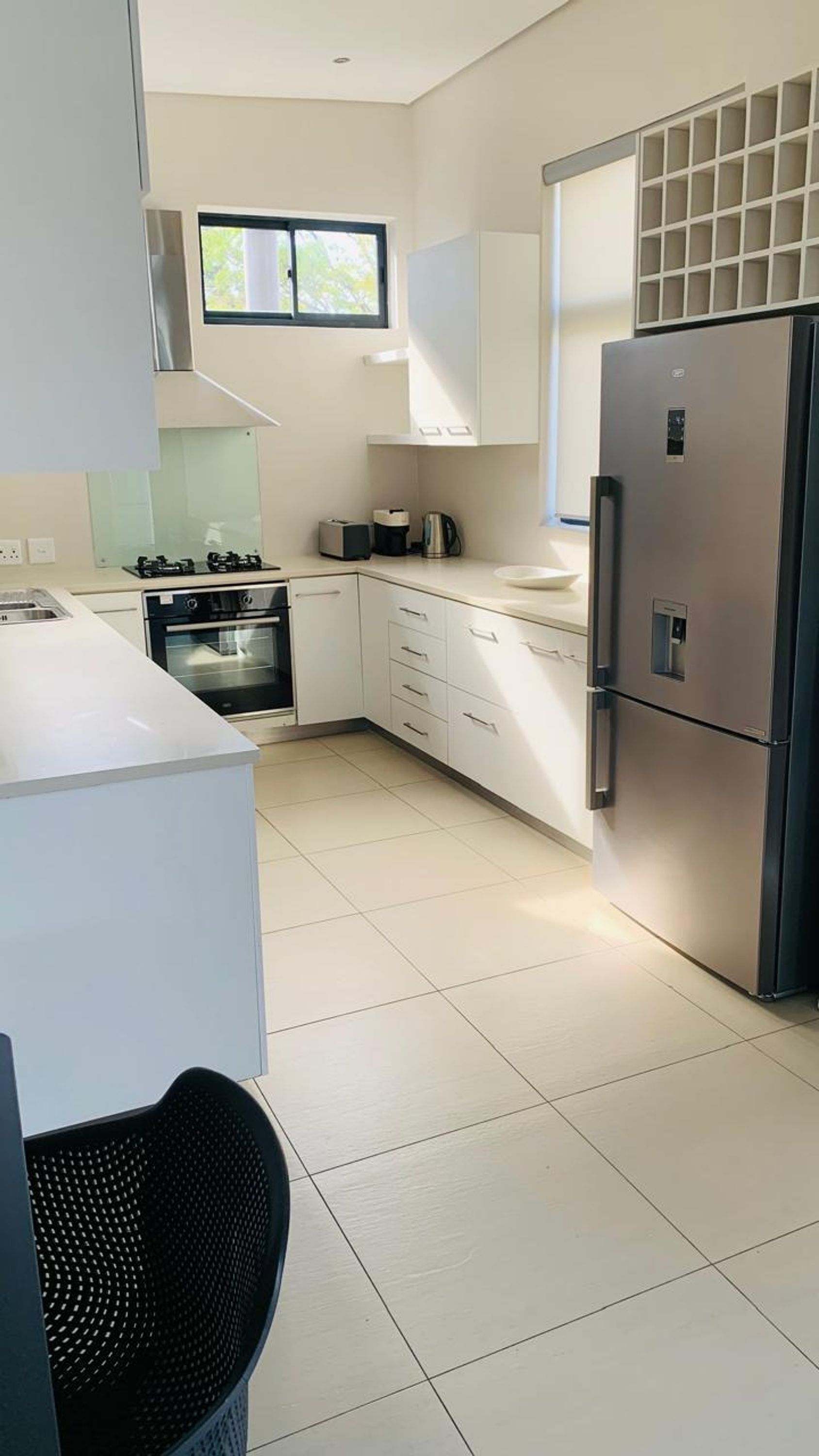 A modern kitchen with white cabinetry, a stainless steel refrigerator, an oven, and a microwave.