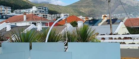 Area piscina sul tetto con vista su una montagna e edifici residenziali sullo sfondo.
