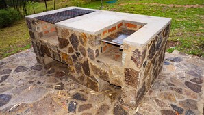 A stone barbecue grill with a metal grate, surrounded by a stone base. - Lovely 3 bed Troutbeck Cottage - 2295 (Nyanga)