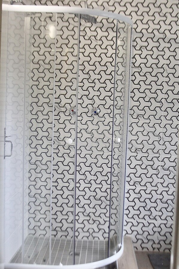 Un espace de douche avec un mur orné d’un motif géométrique.