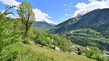 Eine gebirgige Landschaft mit blauem Himmel, einer kurvigen Straße und verstreuten Häusern.