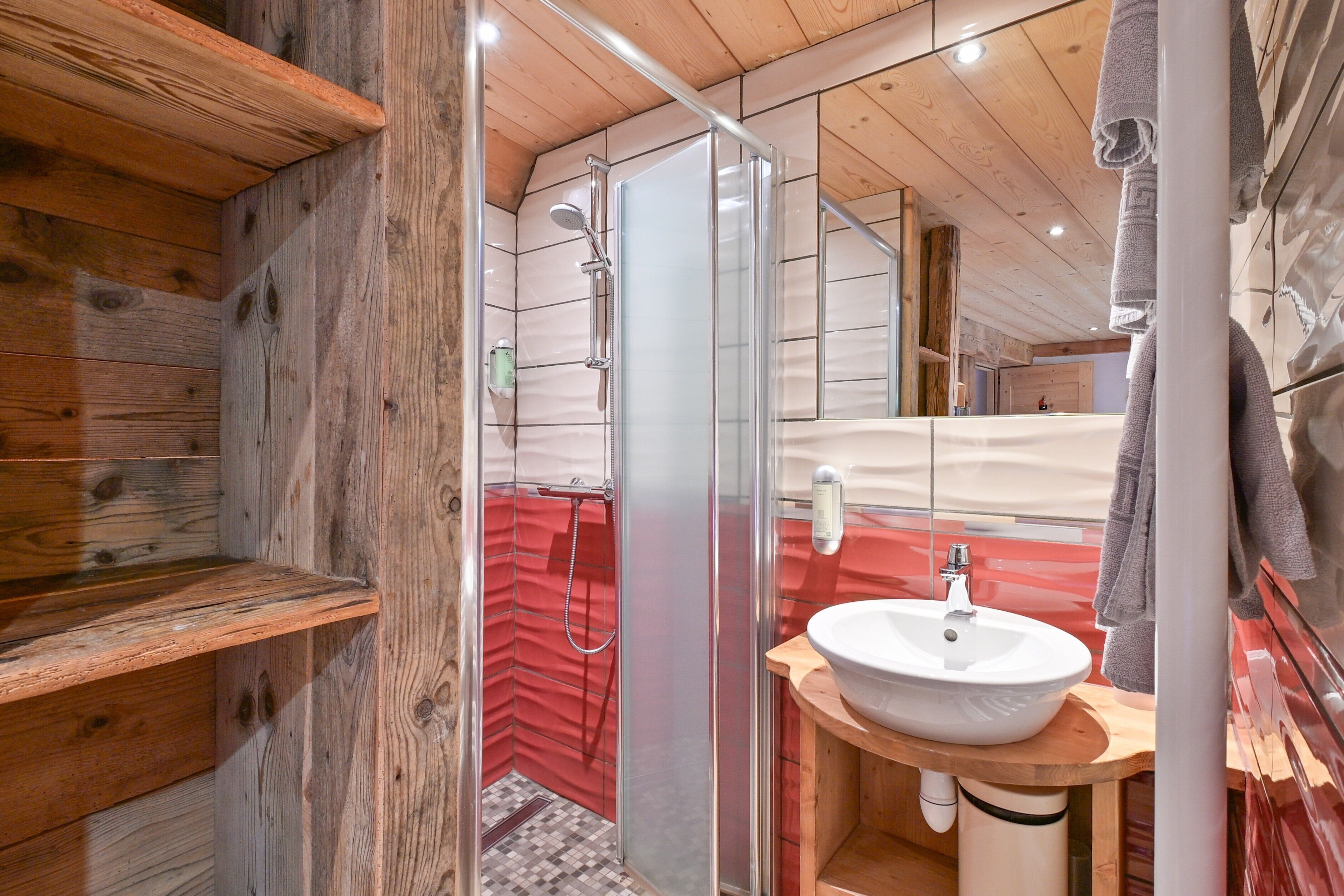Un intérieur en bois avec une douche, un lavabo et un miroir.