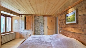 Una habitación con paneles de madera, una cama, una pared de piedra y un cuadro en la pared.