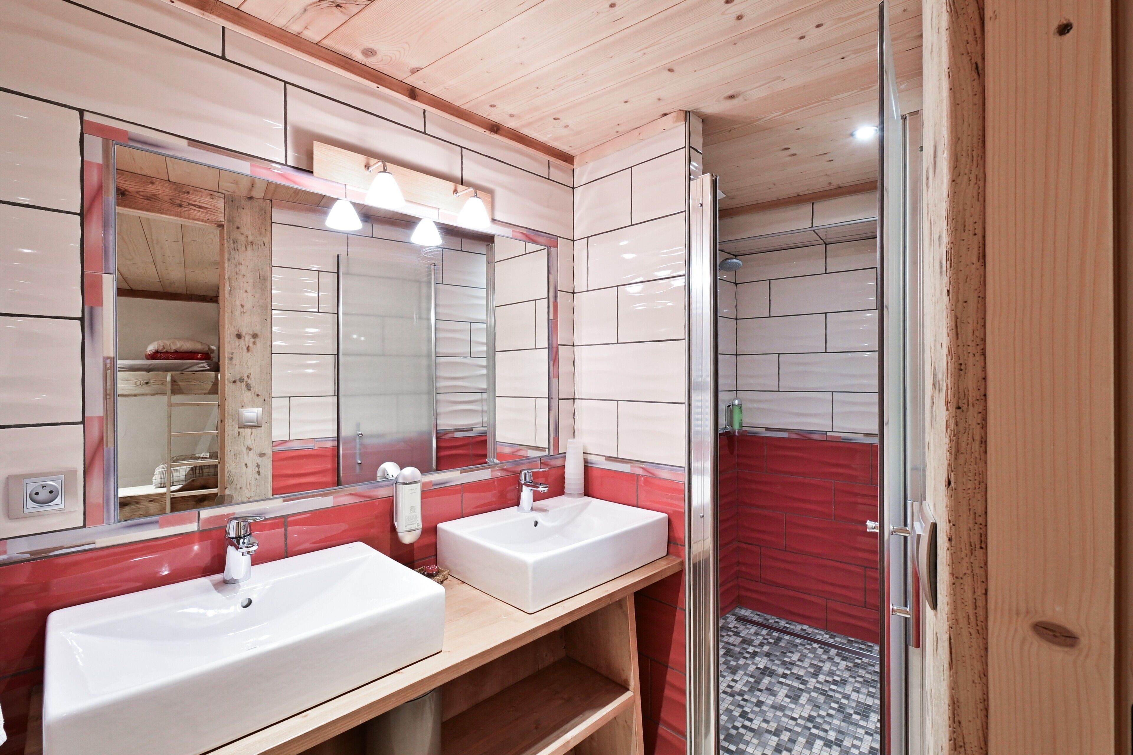 Ein Badezimmer mit zwei Waschbecken, einem großen Spiegel und einer Duschkabine.