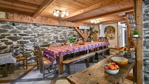 Ein rustikaler Essbereich mit einer Steinwand, Holzbalkendecke und einem Tisch, gedeckt mit einer rot-weißen Tischdecke.