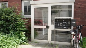 A building with a glass door entrance, a bicycle parked outside, and a small signboard.