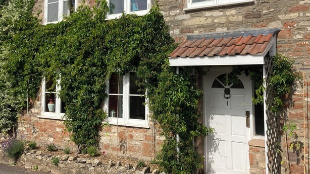 A stone house with a tiled roof, white-framed windows, and a front door. - Traditional Country Cottage (Stanton Drew)